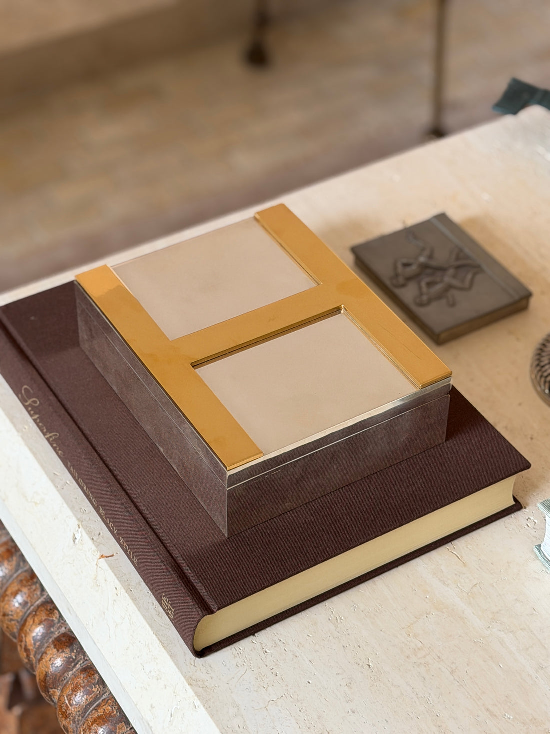 Closed Hermes wood humidor with brass H styled on a leather tailoring book