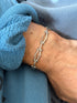 Hinged gated link bracelet on the wrist against a blue sweatshirt cuff, the ball tipped hinge pins catching the light