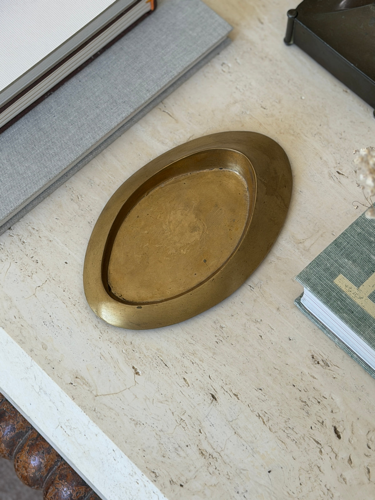 Direct top-down view of low profile Italian bronze oblong vide poche dish styled on travertine surface at Collectors Gene