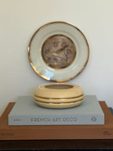 Eye-level front view of cream ceramic ring-shaped decorative bowl with gilt trim at Collectors Gene