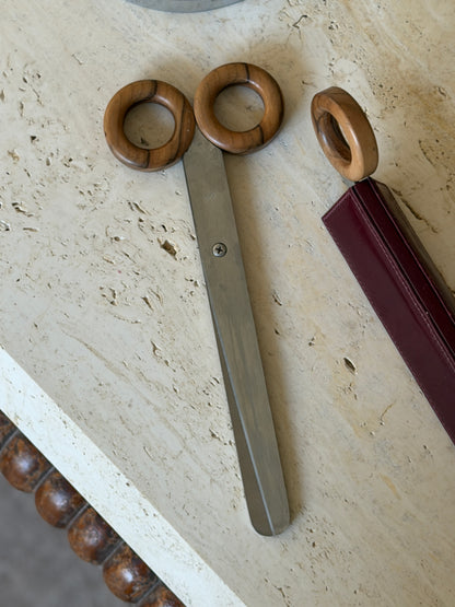 Close view of the scissors with two figured wood ring handles and brushed steel blades, showing the maker&