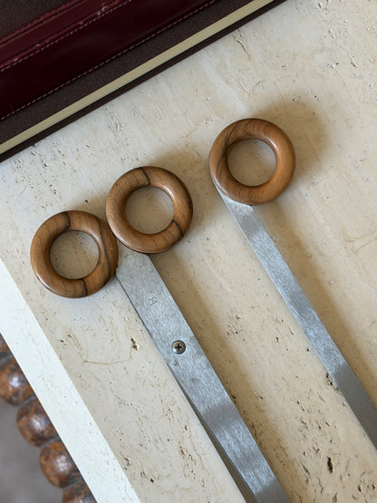 Detail of the three turned wood ring handles showing their dark figured grain, with the stamped maker&