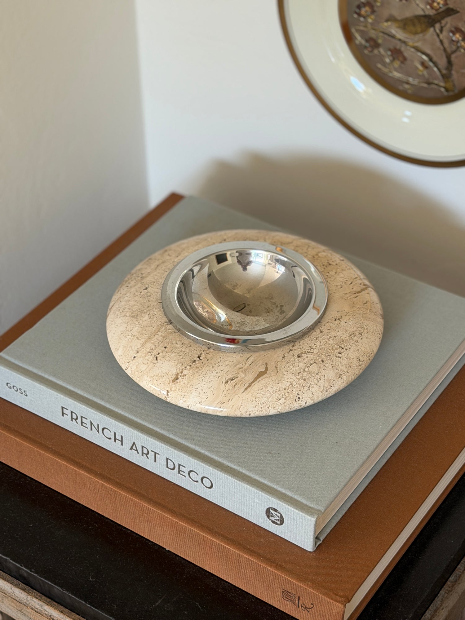 High angle perspective view of round ivory travertine catchall tray displayed on an interior coffee table