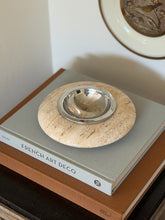 High angle perspective view of round ivory travertine catchall tray displayed on an interior coffee table