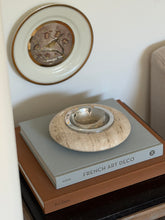 Collectors Gene vintage Italian cream travertine vide poche bowl styled on luxury home interior stack of art books