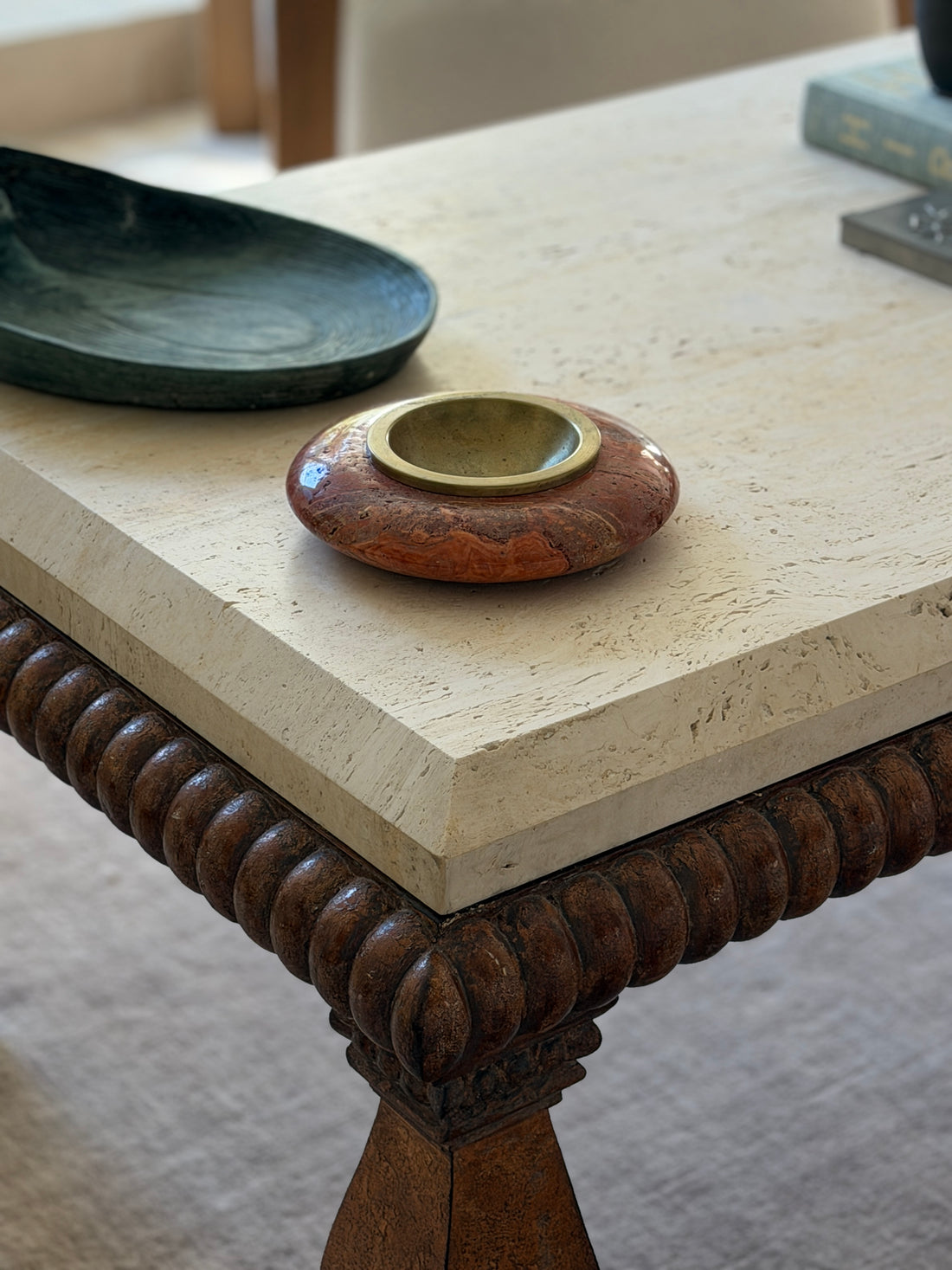 High angle view of red marble travertine catchall tray with brass insert styled on carved wooden coffee table