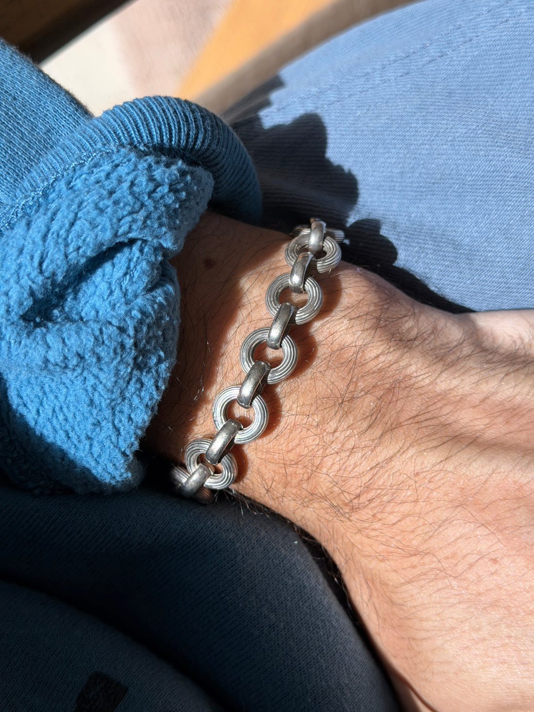 Italian sterling silver bracelet of round ribbed rings joined by smooth oval links, worn on the wrist in sunlight