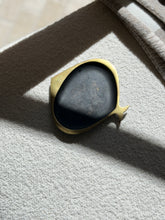 Overhead view of the Hagenauer brass fish ashtray on a cream boucle surface, afternoon light casting a diagonal shadow across its dark patinated well