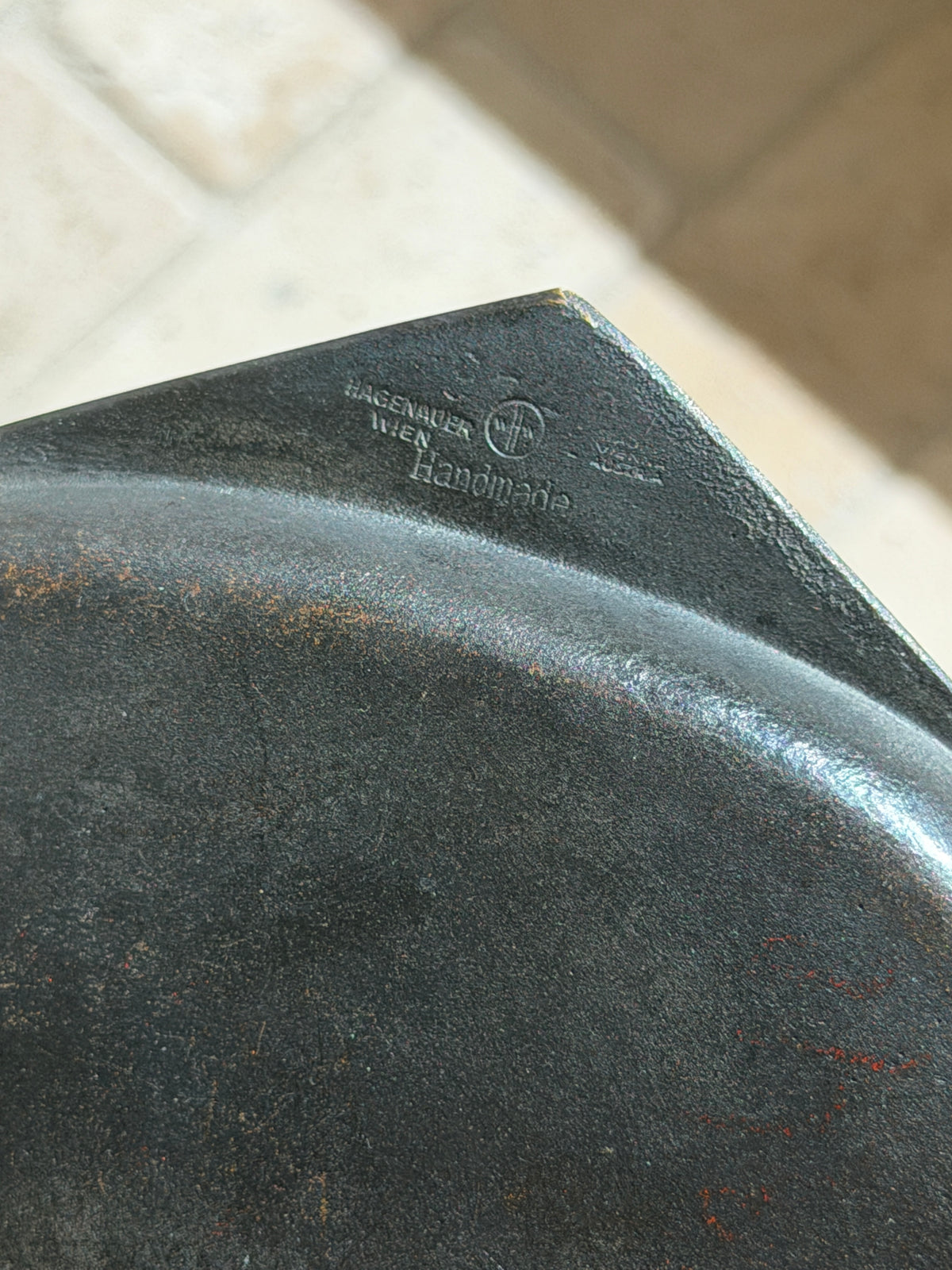 Underside of the Hagenauer ashtray showing the stamped HAGENAUER WIEN mark, the WHW workshop monogram, and the word Handmade on the blackened brass