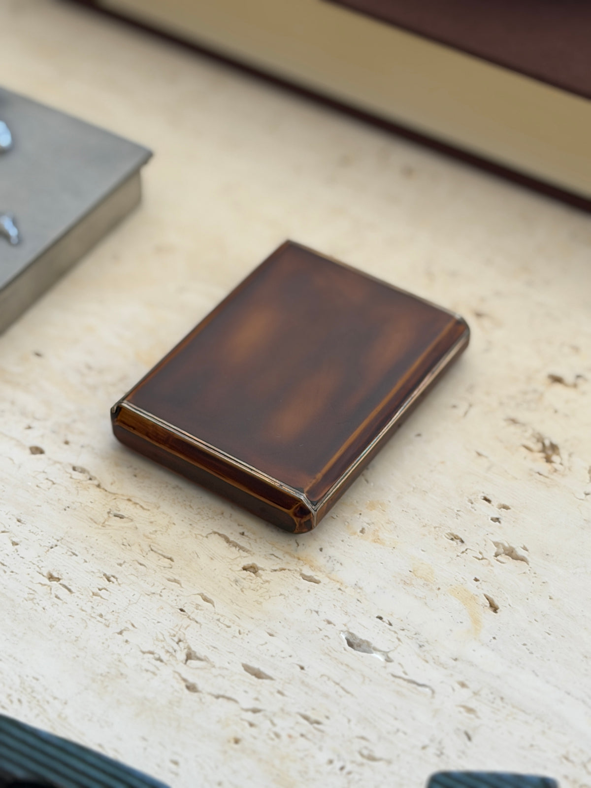 Keller Art Deco box resting on travertine, the lacquer showing subtle depth and a fine silver line around the edges