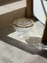 Crystal caviar service dish on stone pavers beside an oak chair leg, sunlight throwing rainbow refractions across the floor