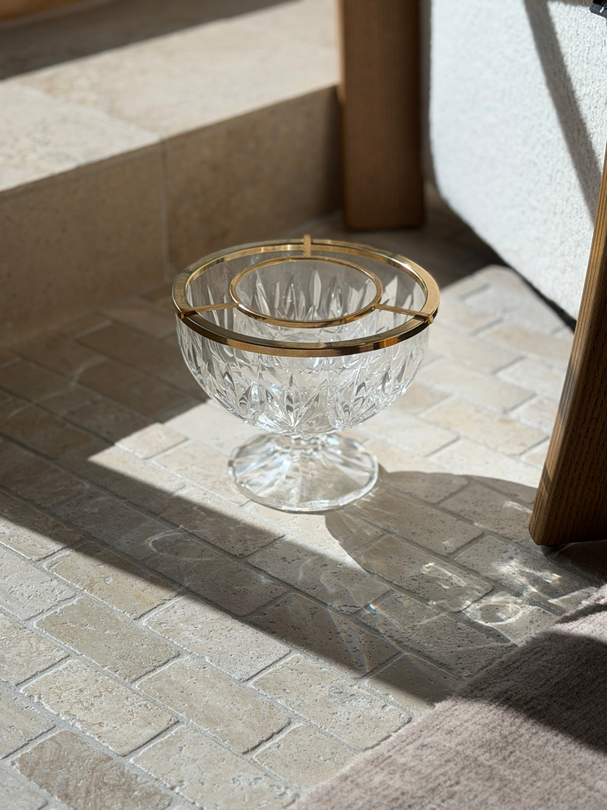 Crystal caviar service dish on stone pavers beside an oak chair leg, sunlight throwing rainbow refractions across the floor