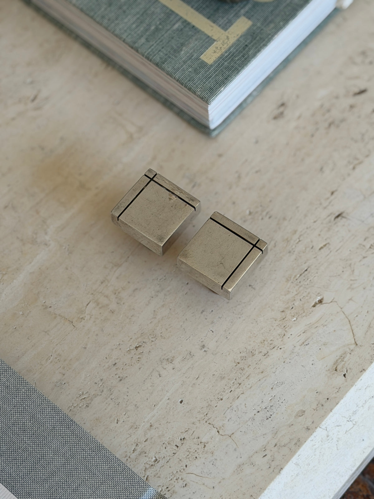 Top-down view of pair of rectangular silver metal bottle stoppers showing linear incised top details