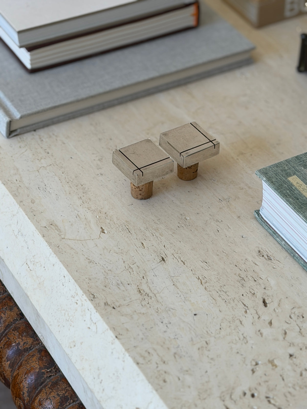 High angle view of two vintage modernist silver and cork wine cork stoppers on light travertine table