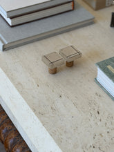 High angle view of two vintage modernist silver and cork wine cork stoppers on light travertine table