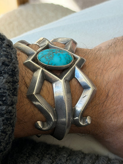 Close angled view of the sand cast cuff on the wrist, showing the matrix veining in the turquoise and the casting texture of the silver