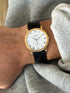 Patek Philippe Calatrava worn on the wrist, close overhead view showing the hobnail bezel and black alligator strap against a gray sweater cuff