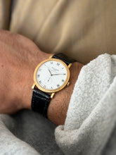 Another close-up of the dial on the wrist, upright, against a khaki sleeve, showing the Roman numeral markers and hobnail bezel detail