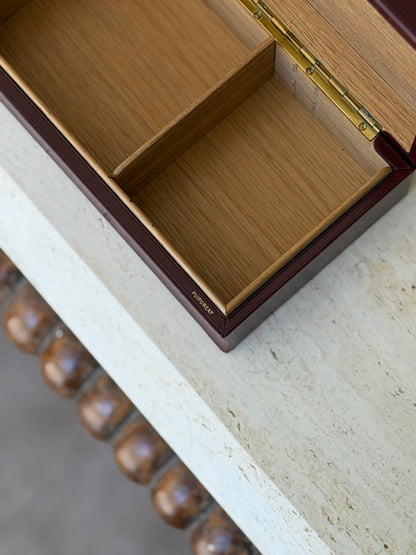 Close-up detail view of open Puiforcat red leather box showing dual-compartment wood lined interior