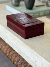 Side profile view of solid red leather Puiforcat French Art Deco desk box resting on marble surface