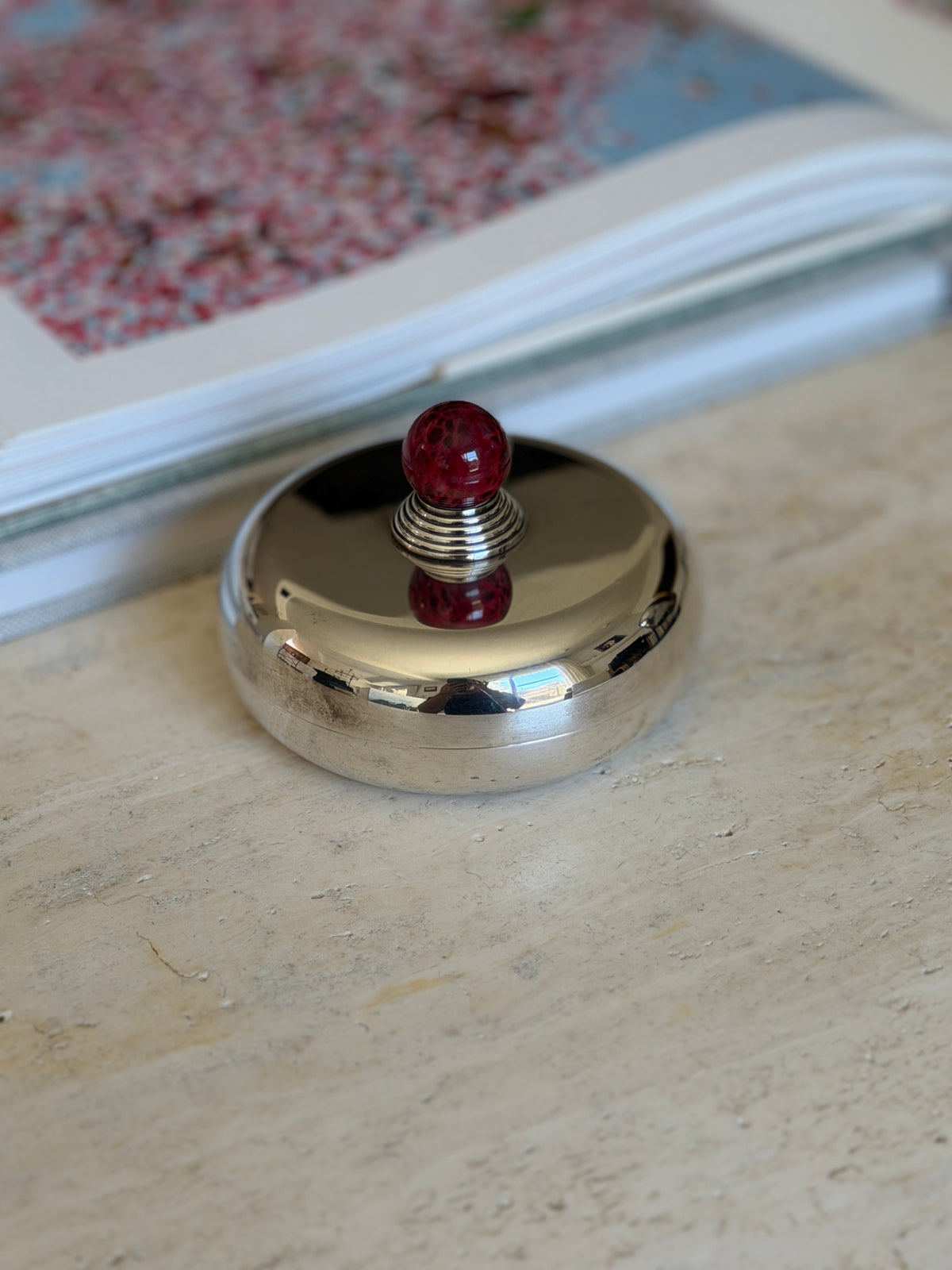 Low side view of the Puiforcat candy dish, showing the rounded pillow shaped body and seam where the lid meets the base