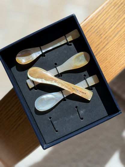 One mother of pearl caviar spoon lifted from its box, the handle engraved RALPH LAUREN across the golden shell