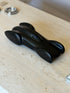 Ralph Lauren Clermont race car sculpture in matte black resin, a streamlined body with teardrop wheel fairings, on a travertine table