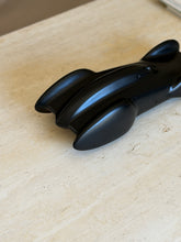 Close view of the rear of the Clermont race car sculpture, the curved tail fins and cockpit opening in soft light
