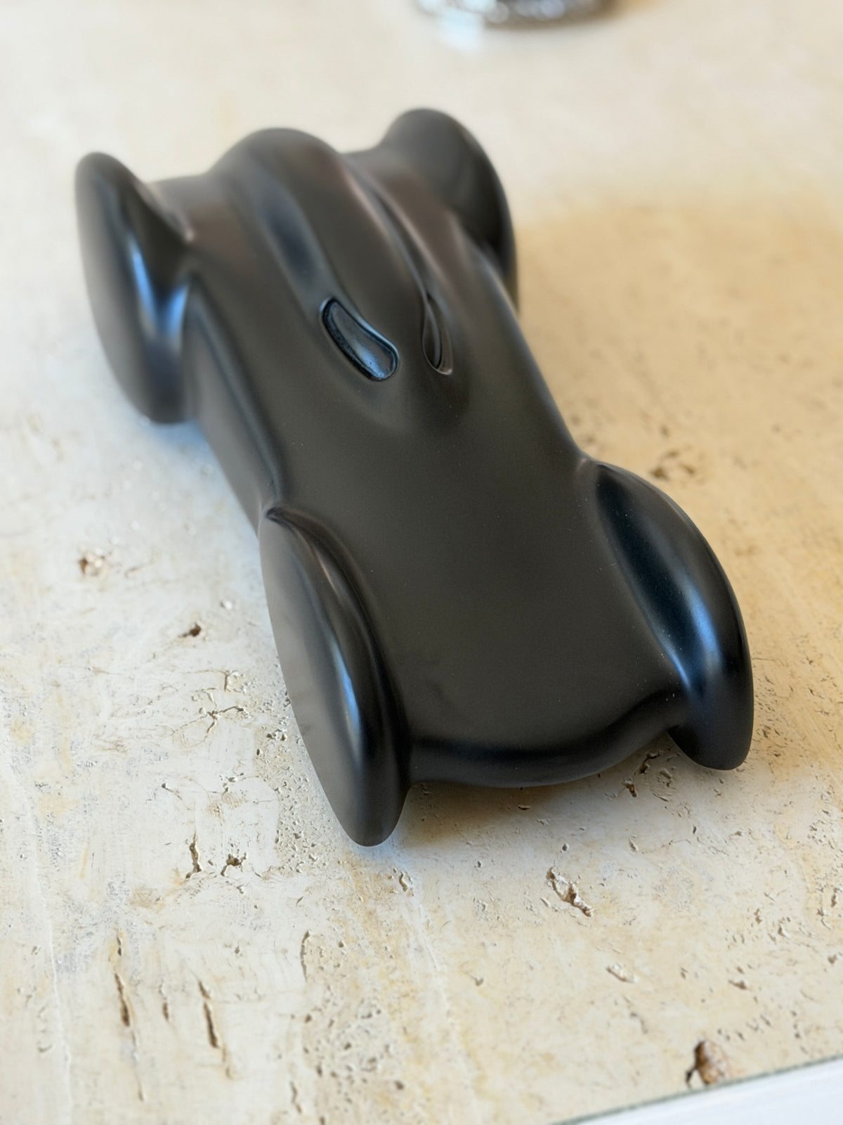 Angled front view of the Ralph Lauren race car on travertine, its rounded nose and swept wheel arches