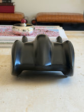 Rear view of the black resin race car, the tail sculpted into three rounded ridges, a silver lidded box with red finial behind