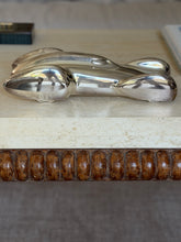 Eye level side profile of the Ralph Lauren race car sculpture on travertine, small wheels beneath the long teardrop body and bobbin turned wood below