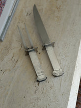 Carving knife and two tine fork from the Venturi set side by side, the knife handle capped with an Ionic scroll and the fork handle ending in a stepped base