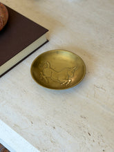 Riccardo Scarpa gilded bronze bowl with a leaping bull in low relief across the shallow well, on travertine beside a brown book
