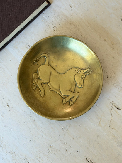 Overhead view of the Scarpa bronze dish, the bull mid leap with curved horns, flicked tail, and finely detailed hooves