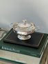Saint Hilaire caviar service on a stack of books including Audemars Piguet, the polished bowl reflecting the room