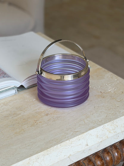 Another angle of the ribbed purple crystal bucket showing the handle and the brown beaded edge of the table it sits on
