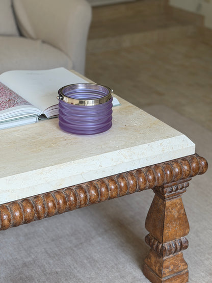 The bucket displayed on a stone-topped coffee table with a carved wooden leg, an open book beside it in a living room setting