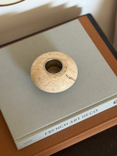 Top-down view of round carved beige travertine stone catchall showing recessed center detail on book display