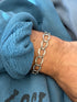 Sterling silver horseshoe link bracelet worn on the wrist against a blue fleece cuff, each horseshoe stamped with nail holes