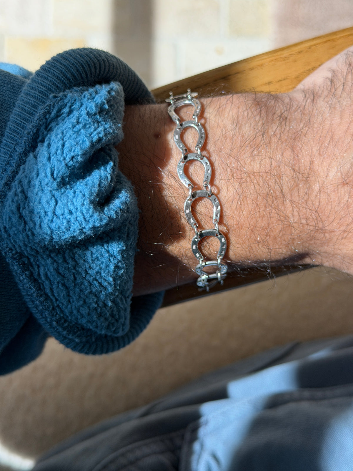 Close wrist view of the sterling horseshoe bracelet, the jump rings joining each shoe and the box clasp end visible