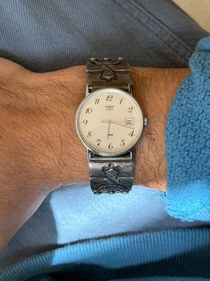 Sterling silver watch cuff with stamped winged figures and turquoise cabochons, fitted with a Timex Quartz watch with a cream dial