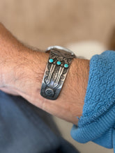 Close up of the cuff end on the wrist, two applied arrows with a zigzag between them above a stamped sun symbol