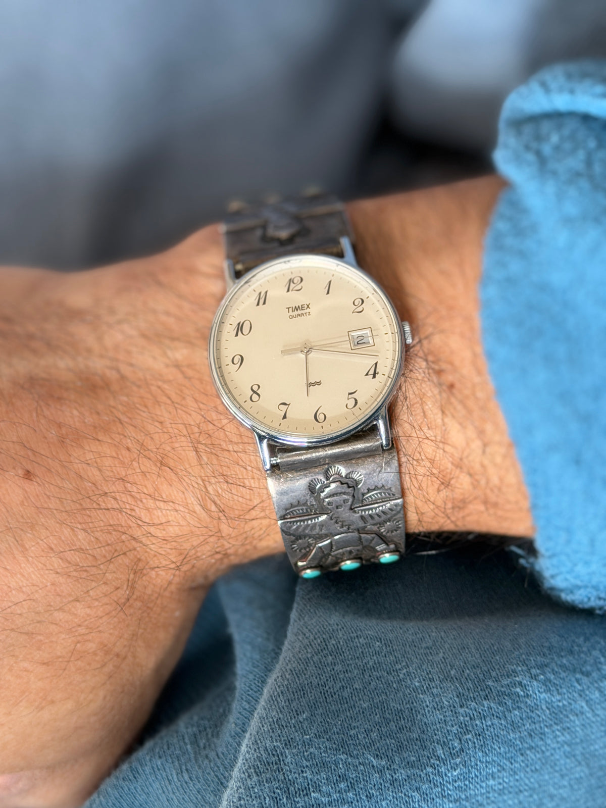 Front view of the Timex watch set in the sterling cuff on the wrist, the oxidized stamped figures framing the dial