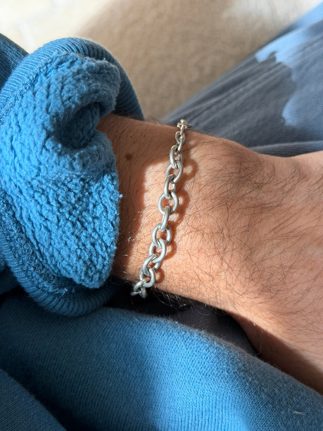 Chunky sterling silver open link bracelet worn on the wrist in bright sun, rounded oval links with a soft brushed finish