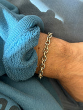 Open link sterling bracelet on the wrist against a blue fleece cuff and gray twill, showing the heavy rounded links