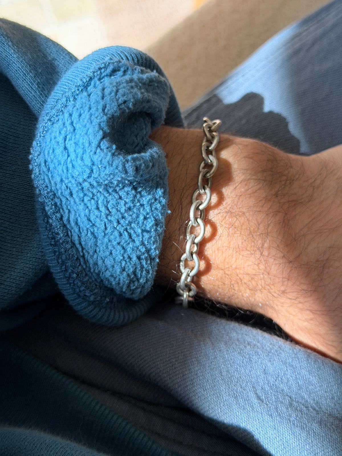 Sterling silver open link bracelet on the wrist in raking light, the satin links casting small shadows on the skin