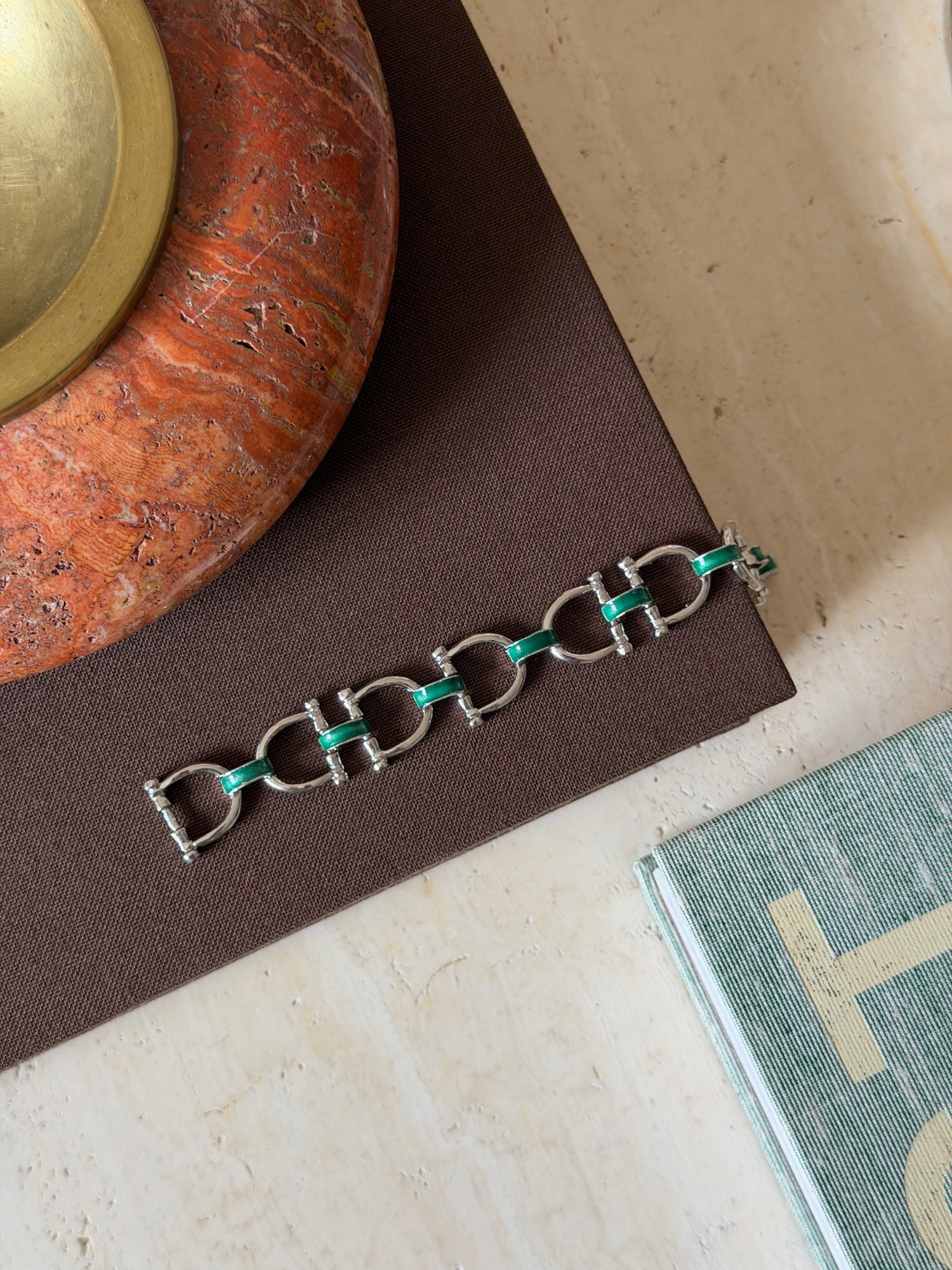 Close-up detail of the green enamel snaffle bit charm on the bracelet