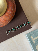 Close-up detail of the green enamel snaffle bit charm on the bracelet