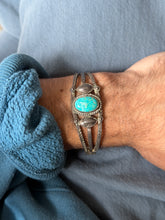 Wrist view of the triple band cuff against blue twill, showing the split shank, domed leaves, and stamped outer bands