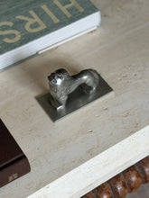 Overhead angled view of the lion from the opposite side, facing downward with its tail curving toward the base